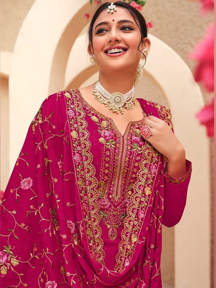 "Women fashion model wearing a vibrant pink embroidered ethnic suit with floral dupatta and traditional jewelry, showcasing elegant Indian festive wear."