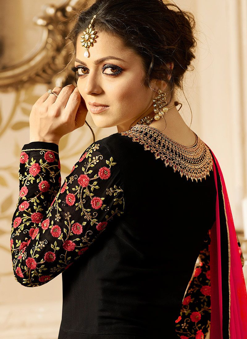 "Women fashion model wearing a black embroidered ethnic outfit with floral detailing, statement jewelry, and elegant traditional styling."