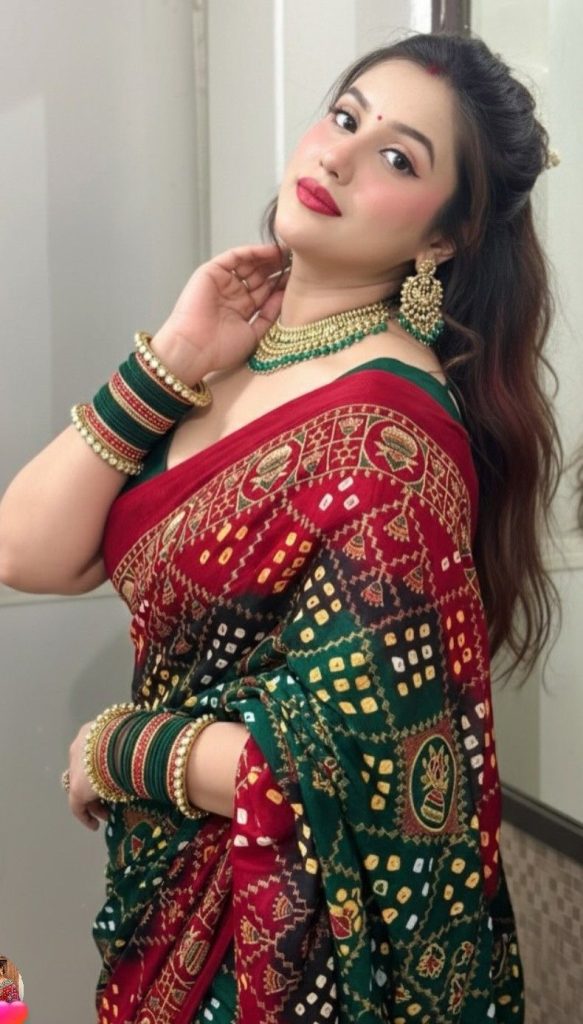 Woman wearing a peach embroidered designer saree standing beside a pillar.